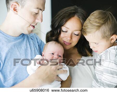 Stock Photograph - Mother and father carrying son (4-5) and daughter (0-1 months). Fotosearch