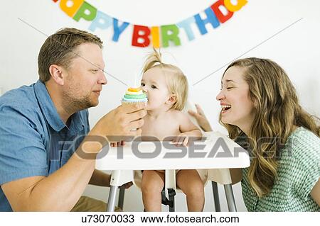 Stock Image - Mother and father celebrating first birthday of daughter (12-17 months). Fotosearch