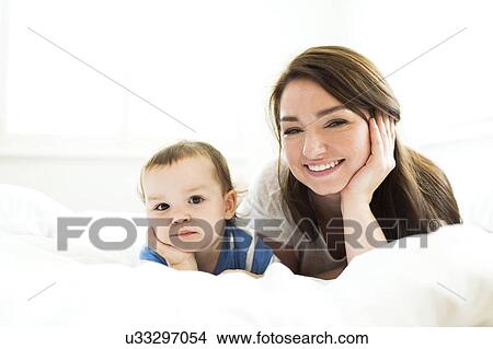 Picture - Mother and son (4-5) lying on bed. Fotosearch