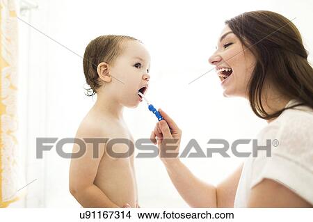 Picture - Mother brushing son (4-5) teeth. Fotosearch