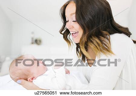 Mother carrying daughter (0-1 months) and laughing View Large Photo Image Stock Image - Mother carrying daughter (0-1 months) and laughing. Fotosearch