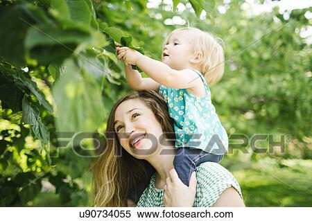 Mother carrying daughter (12-17 months) on shoulders View Large Photo Image Stock Photography - Mother carrying daughter (12-17 months) on shoulders. Fotosearch