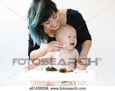 Mother cleaning baby boy (12-17 months) from cupcake View Large Photo Image Stock Photo - Mother cleaning baby boy (12-17 months) from cupcake. Fotosearch