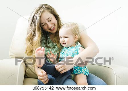 Mother dressing daughter (11-17 months) in living room View Large Photo Image Stock Image - Mother dressing daughter (11-17 months) in living room. Fotosearch