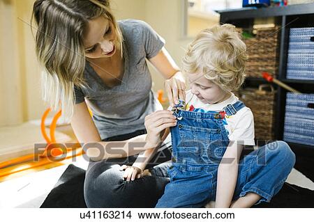 Picture - Mother dressing son (4-5). Fotosearch