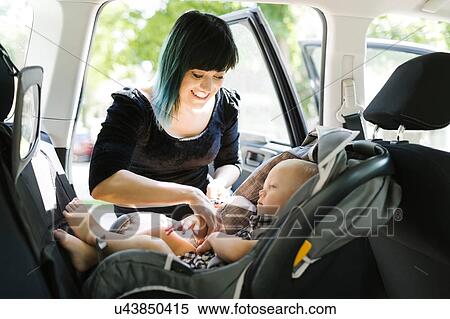 Mother fastening baby boy (12-17 months) in car seat View Large Photo Image Stock Photography - Mother fastening baby boy (12-17 months) in car seat. Fotosearch