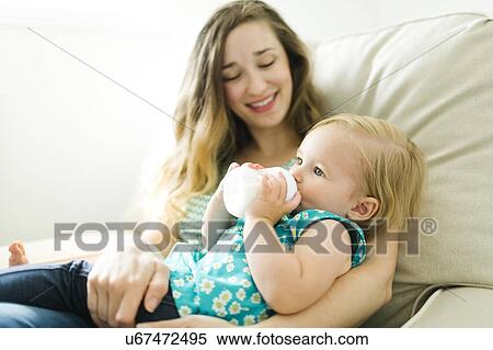 Mother feeding baby girl (12-17 months) in living room View Large Photo Image Stock Photography - Mother feeding baby girl (12-17 months) in living room. Fotosearch