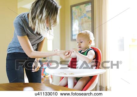 Stock Image - Mother feeding son (12-17 months) with breakfast cereals. Fotosearch