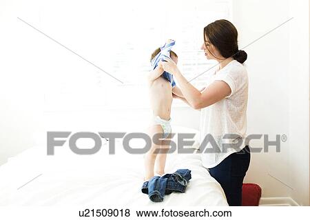 Stock Photo - Mother helping son (4-5) dress. Fotosearch