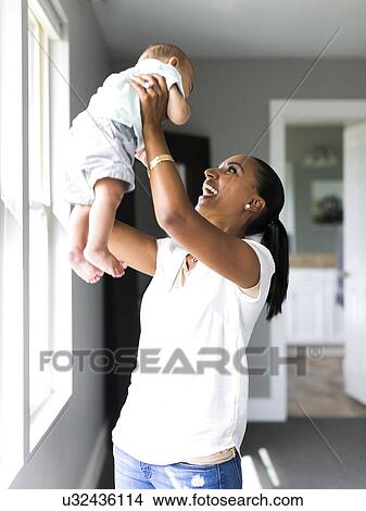 Picture - Mother holding aloft baby boy (2-5 months). Fotosearch