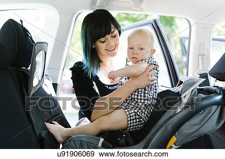 Mother holding baby boy (12-17 months) in car View Large Photo Image Stock Photo - Mother holding baby boy (12-17 months) in car. Fotosearch