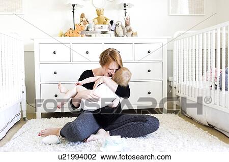 Mother holding son (12-17 months) in nursery View Large Photo Image Stock Image - Mother holding son (12-17 months) in nursery. Fotosearch
