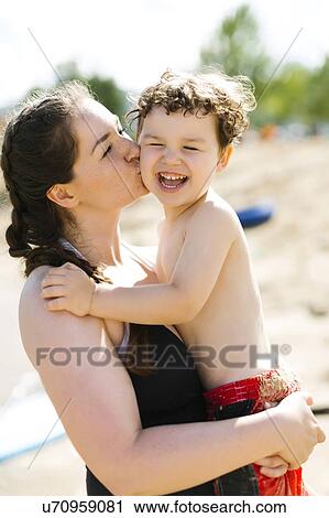 Mother kissing son (4-5) on beach View Large Photo Image Stock Image - Mother kissing son (4-5) on beach. Fotosearch