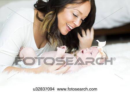 Mother playing with daughter (0-1 months) on bed View Large Photo Image Picture - Mother playing with daughter (0-1 months) on bed. Fotosearch