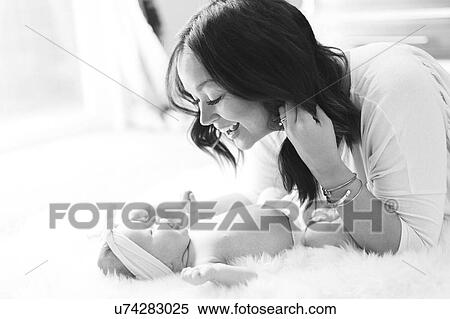 Stock Photography - Mother playing with daughter (0-1 months) on bed. Fotosearch