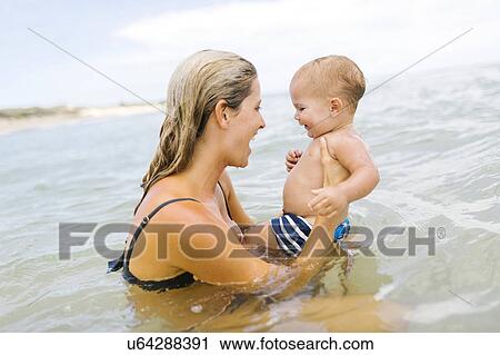 Stock Image - Mother playing with son (12-17 months) in sea. Fotosearch