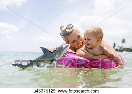 Stock Photo - Mother playing with son (12-17 months) in sea. Fotosearch