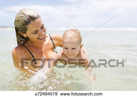 Mother playing with son (12-17 months) in sea View Large Photo Image Stock Photo - Mother playing with son (12-17 months) in sea. Fotosearch