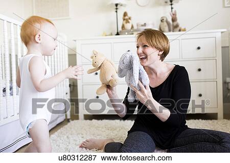 Mother playing with son (12-17 months) in nursery View Large Photo Image Stock Photo - Mother playing with son (12-17 months) in nursery. Fotosearch