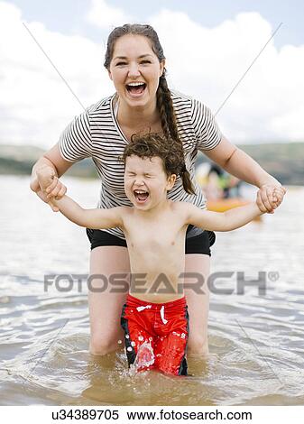 Stock Photography - Mother playing with son (4-5) in lake. Fotosearch
