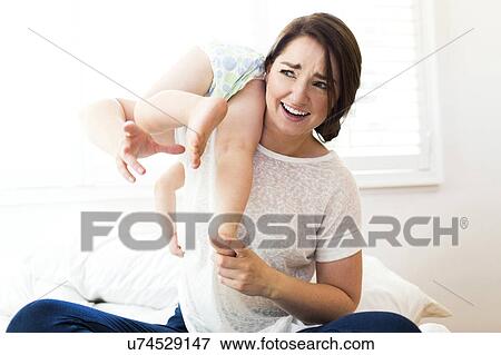 Stock Photo - Mother playing with son (4-5) on bed. Fotosearch