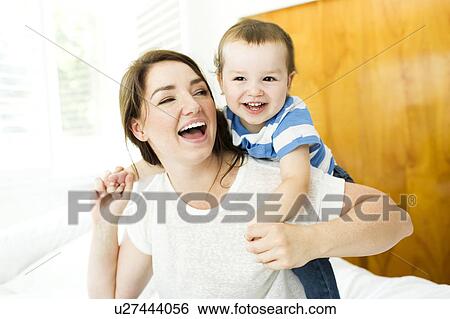Mother playing with son (4-5) on bed View Large Photo Image Stock Photograph - Mother playing with son (4-5) on bed. Fotosearch