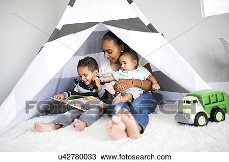 Stock Image - Mother playing with sons (2-5 months, 2-3) in toy tent. Fotosearch