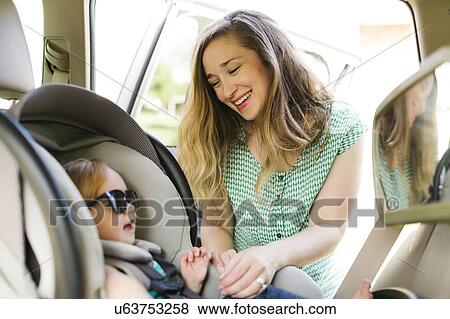 Stock Photo - Mother preparing baby girl (12-17 months) for car trip. Fotosearch