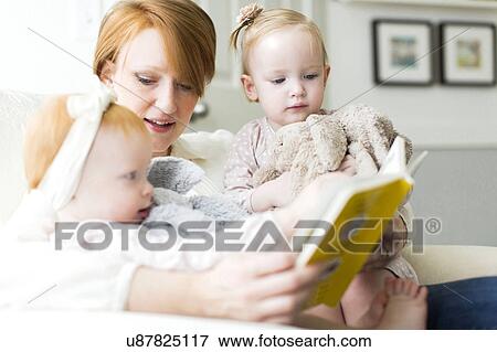 Stock Photo - Mother reading book to daughters ( 12-17 months ). Fotosearch