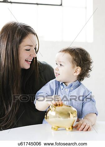 Mother teaching son (4-5) how to save money View Large Photo Image Stock Photograph - Mother teaching son (4-5) how to save money. Fotosearch