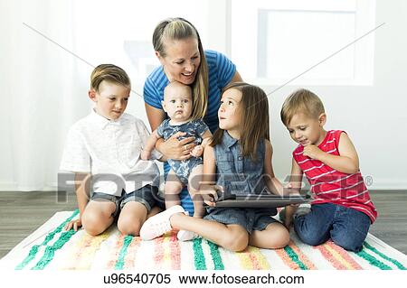 Stock Photography - Mother with children (6-11 months, 2-3, 6-7) using digital tablet at home. Fotosearch