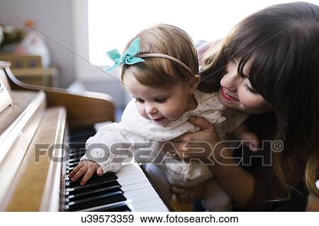 Stock Photo - Mother with daughter (12-17 months) playing piano. Fotosearch