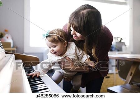 Mother with daughter (12-17 months) playing piano View Large Photo Image Stock Photograph - Mother with daughter (12-17 months) playing piano. Fotosearch