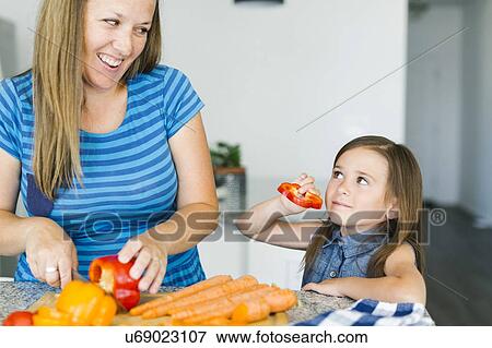 Stock Photo - Mother with daughter (6-7) preparing food. Fotosearch