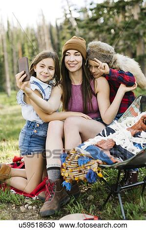 Stock Image - Mother with son (6-7) and daughter (8-9) camping in forest. Fotosearch