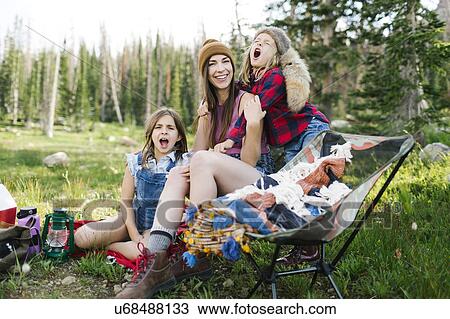 Stock Image - Mother with son (6-7) and daughter (8-9) camping in forest. Fotosearch