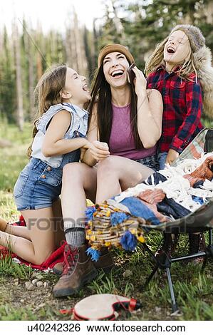 Stock Photograph - Mother with son (6-7) and daughter (8-9) camping in forest. Fotosearch