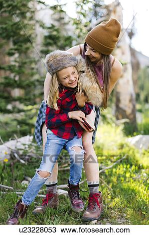 Stock Image - Mother with son (6-7) rough housing in forest. Fotosearch