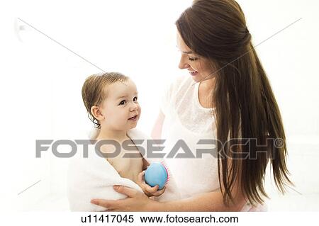 Stock Photography - Mother wrapping son (4-5) in towel in bathroom. Fotosearch