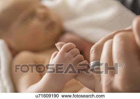 Stock Image - Newborn son (0-1 month) holding father's finger. Fotosearch