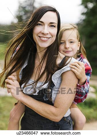 Stock Photo - Outdoor portrait of mother playing carrying son (6-7). Fotosearch