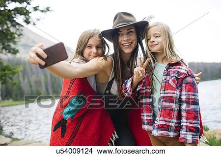 Outdoor portrait of mother with kids (6-7, 8-9) taking selfie by lake View Large Photo Image Picture - Outdoor portrait of mother with kids (6-7, 8-9) taking selfie by lake. Fotosearch