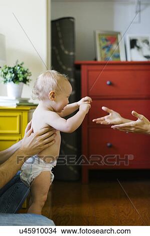 Picture - Parents assisting in son's (12-17 months) first step. Fotosearch