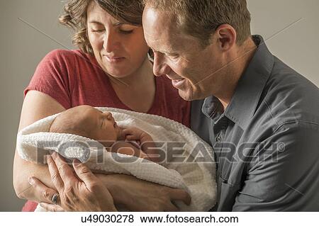 Parents holding and looking at baby son (0-1 months) View Large Photo Image Stock Photo - Parents holding and looking at baby son (0-1 months). Fotosearch