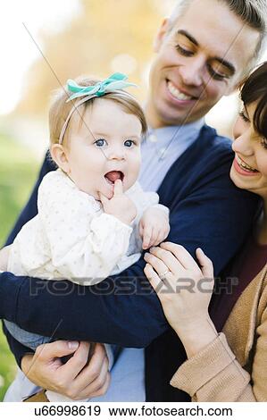 Stock Photo - Parents holding daughter (12-17 months). Fotosearch