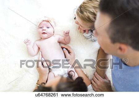 Stock Image - Parents lying on bed with son (4-5) and daughter (0-1 months). Fotosearch