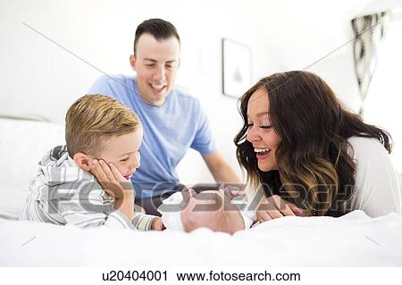 Stock Image - Parents son (4-5) and daughter ( 1 month) in bedroom. Fotosearch