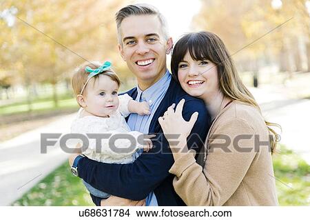 Picture - Parents with daughter (12-17 months) in park. Fotosearch