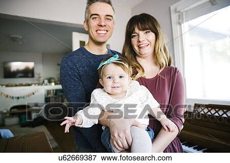 Stock Photo - Parents with daughter (12-17 months) in living room. Fotosearch