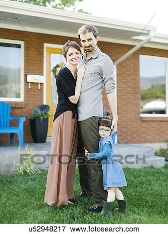 Parents with daughter (2-3) standing in front of house View Large Photo Image Stock Photo - Parents with daughter (2-3) standing in front of house. Fotosearch